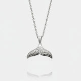 Silver whale tail pendant on a chain against a white background