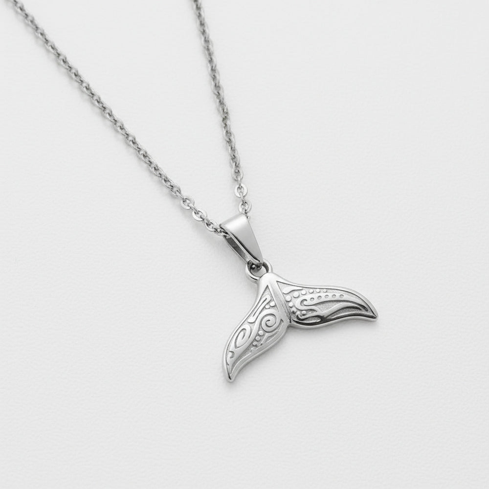 Silver whale tail pendant on a chain against a light gray background