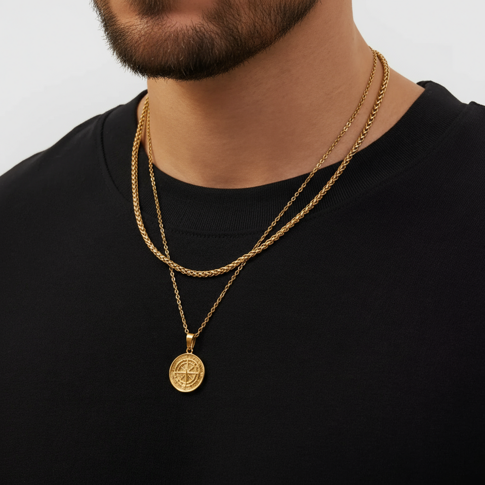 Man wearing a gold necklace with a pendant on a plain background