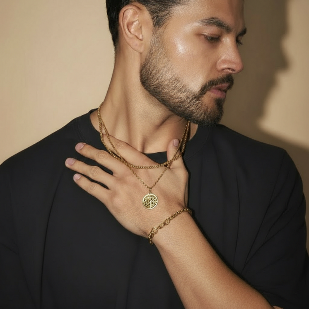 Man wearing gold necklaces and a bracelet against a neutral background