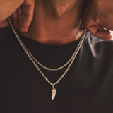 Close-up of a person wearing a silver chain necklace with an angel wing pendant.