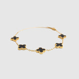 Gold bracelet with black clover-shaped charms on a white background