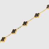 Gold chain bracelet with black clover-shaped charms on a white background