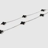 Silver necklace with black clover-shaped pendants on a white background