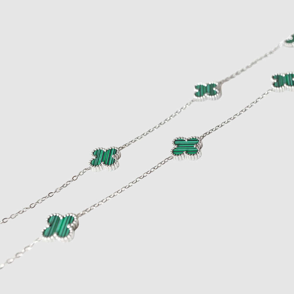 Silver chain necklace with green butterfly pendants on a light gray background