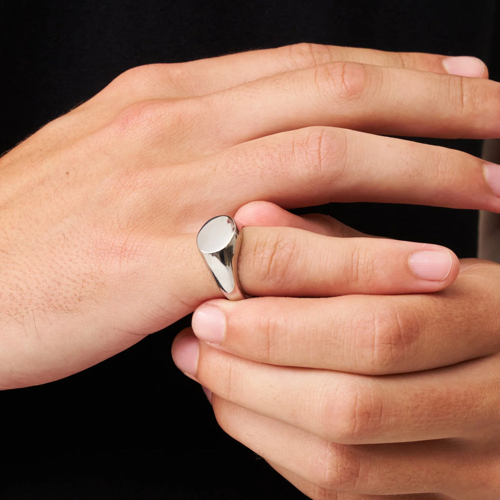 Close-up of a hand wearing a silver ring on a black background