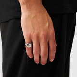 Hand wearing a silver ring with a plain background