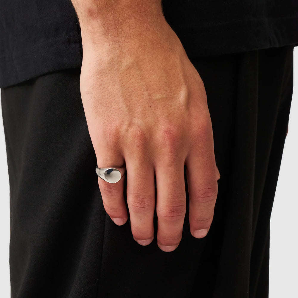Hand wearing a silver ring with a plain background