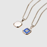 Two silver necklaces with hexagonal pendants on a wooden surface