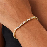 Gold bracelet with clear stones on a wrist against a neutral background