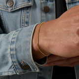 Gold bracelet on a wrist with a denim jacket