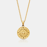 Gold compass necklace on a light gray background