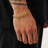 Gold chain bracelet on a wrist with a black background