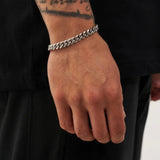 Hand wearing a silver chain bracelet on a black background