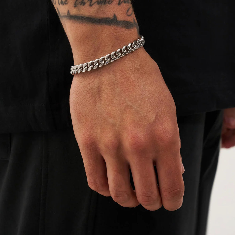 Hand wearing a silver chain bracelet on a black background