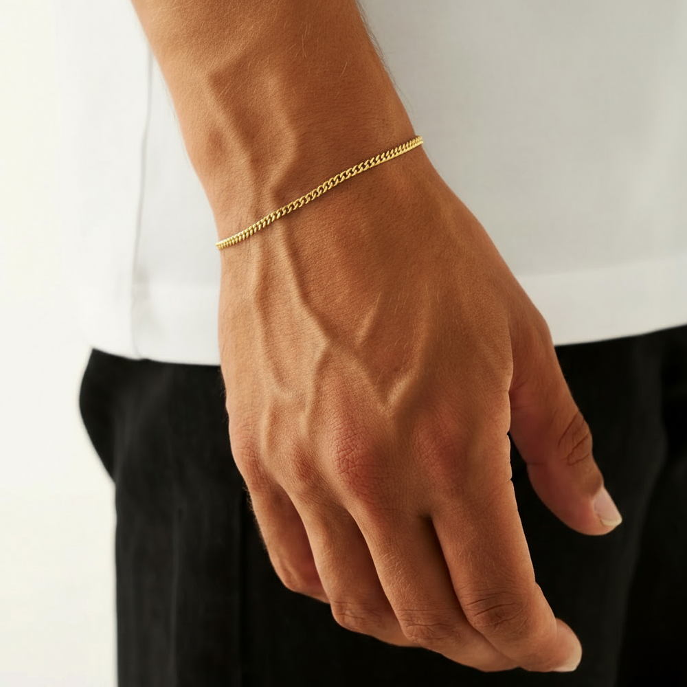 Hand wearing a gold bracelet on a plain background