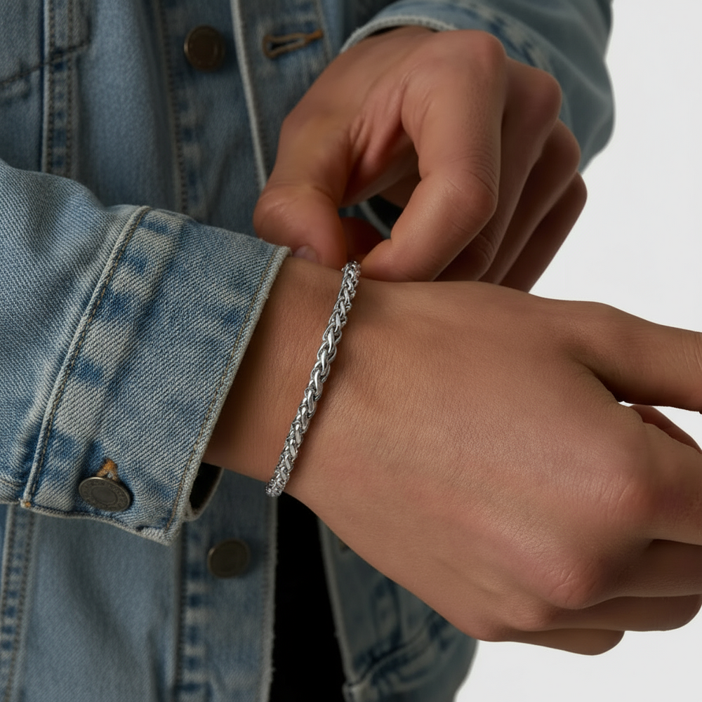 Person wearing a silver bracelet on a neutral background