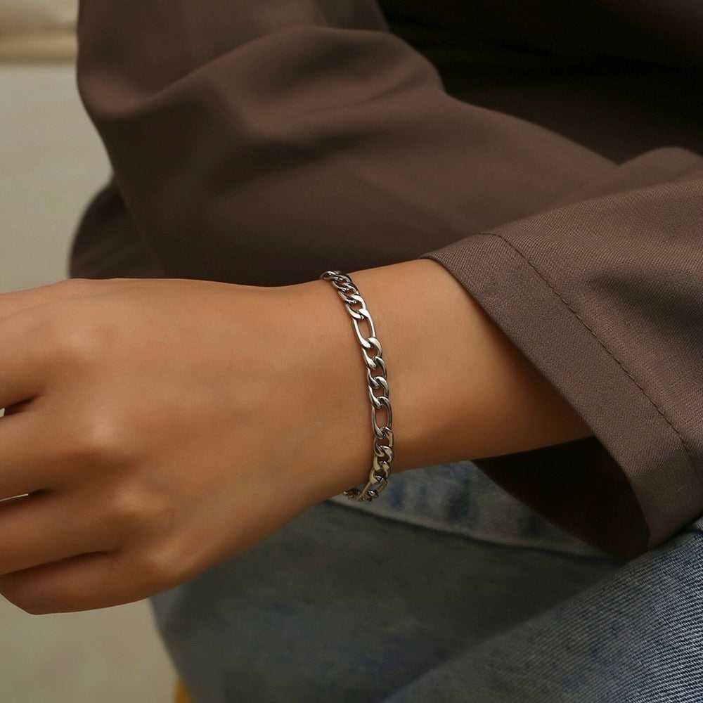 Person wearing a silver chain bracelet on a neutral background