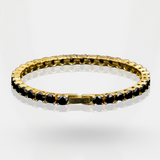 Gold bracelet with black beads on a light gray background