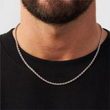Silver chain necklace worn by a person on a plain background