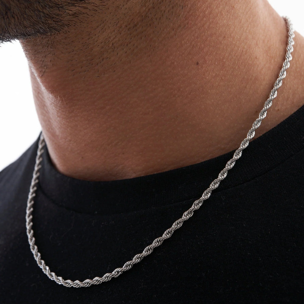 Silver chain necklace worn by a person on a black background