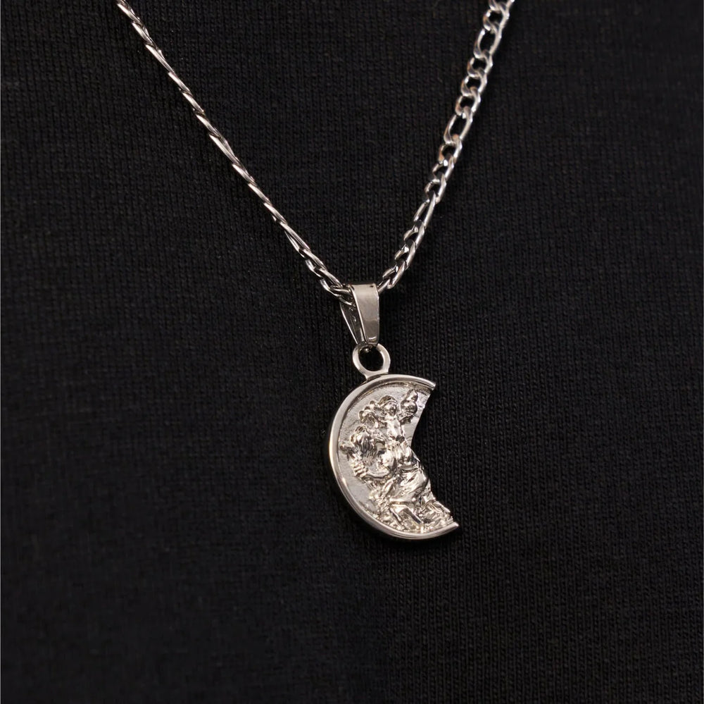 Silver necklace with a crescent moon pendant on a black background