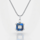 Silver necklace with a blue pendant featuring a central diamond on a white background