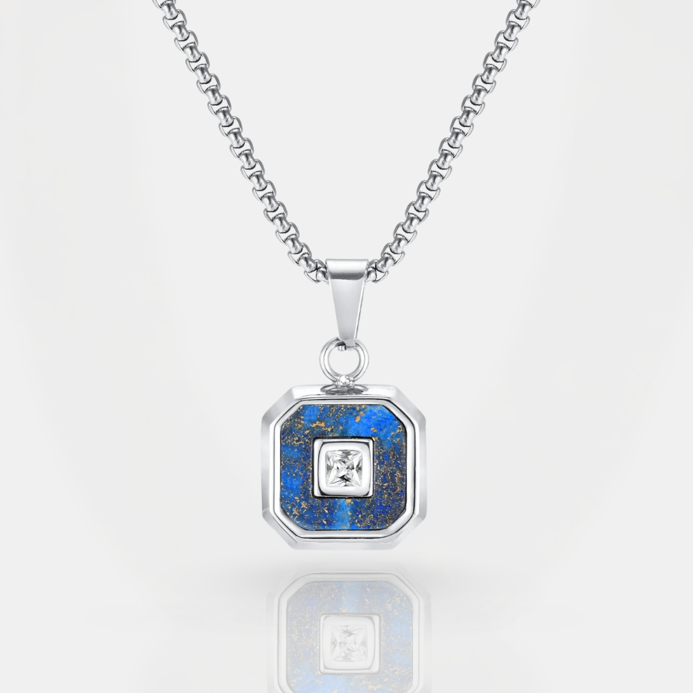 Silver necklace with a blue pendant featuring a central diamond on a white background