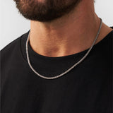 Man wearing a silver chain necklace against a plain background