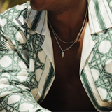 Person wearing a patterned jacket with sunglasses and a blurred outdoor background