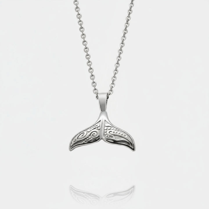 Silver whale tail pendant on a chain against a white background