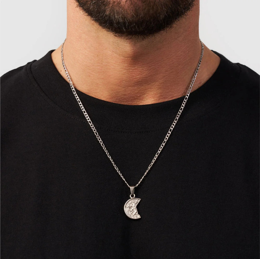 Man wearing a black shirt with a silver necklace featuring a moon pendant.
