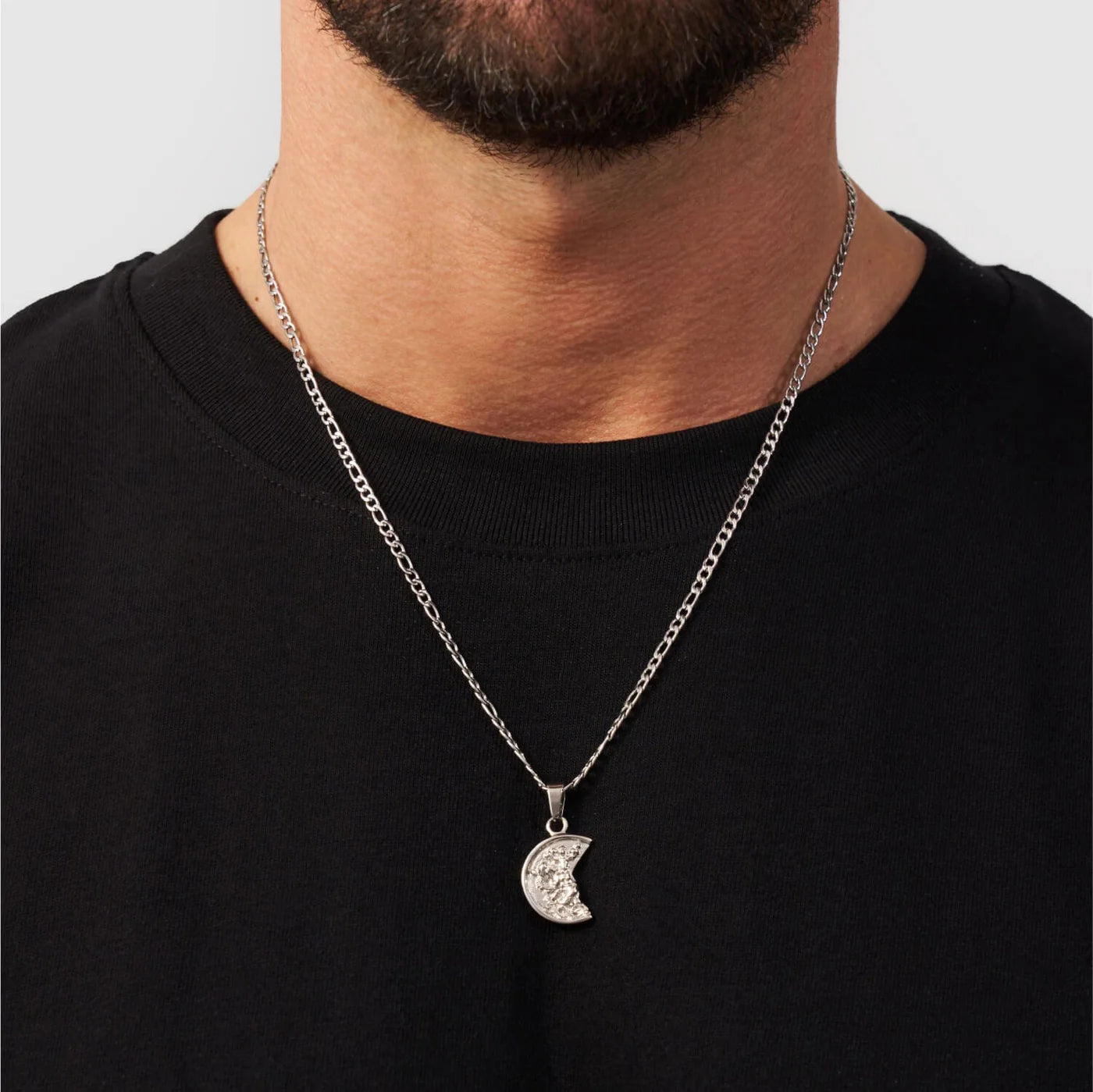 Man wearing a black shirt with a silver necklace featuring a moon pendant.