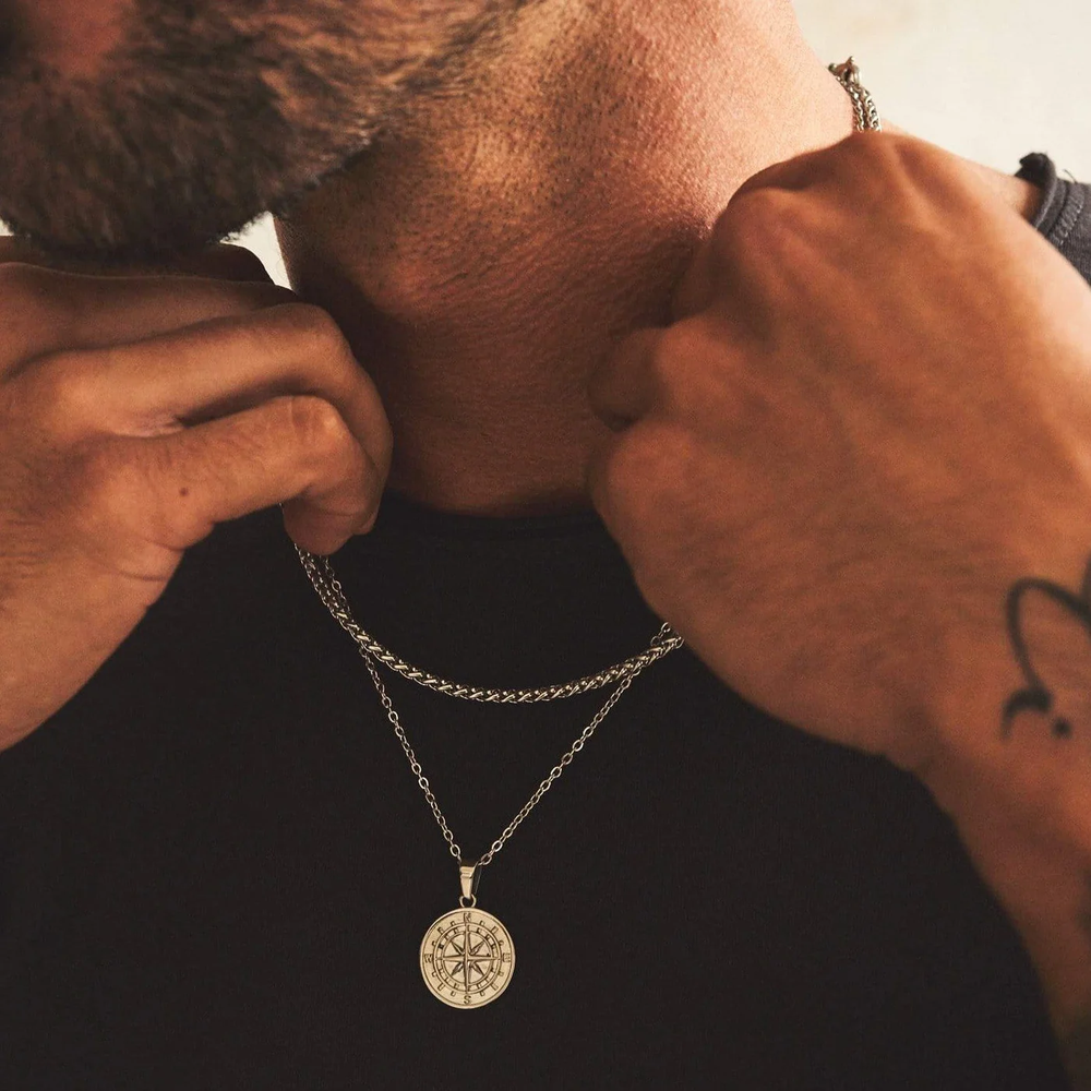 Person adjusting a necklace with a pendant on a dark background