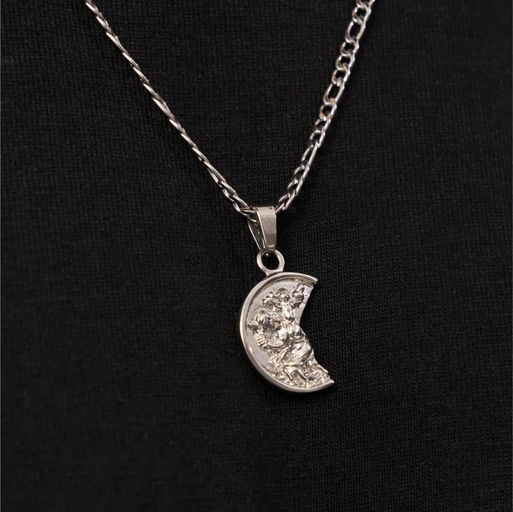Silver necklace with a crescent moon pendant on a black background